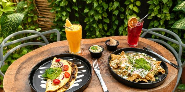Mesa con comida mexicana y bebidas refrescantes en un ambiente al aire libre.