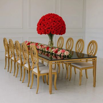 Mesa de acero inoxidable color dorado y vidrio templado negro, sillas Valentina color dorado, flores