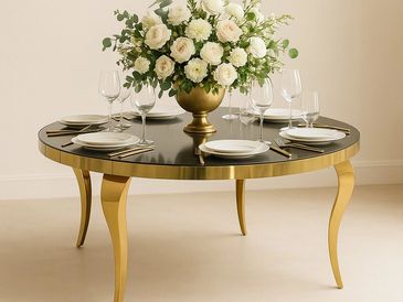 Mesa redonda dorada de lujo con vidrio negro con arreglo floral, platos y cubiertos dorados