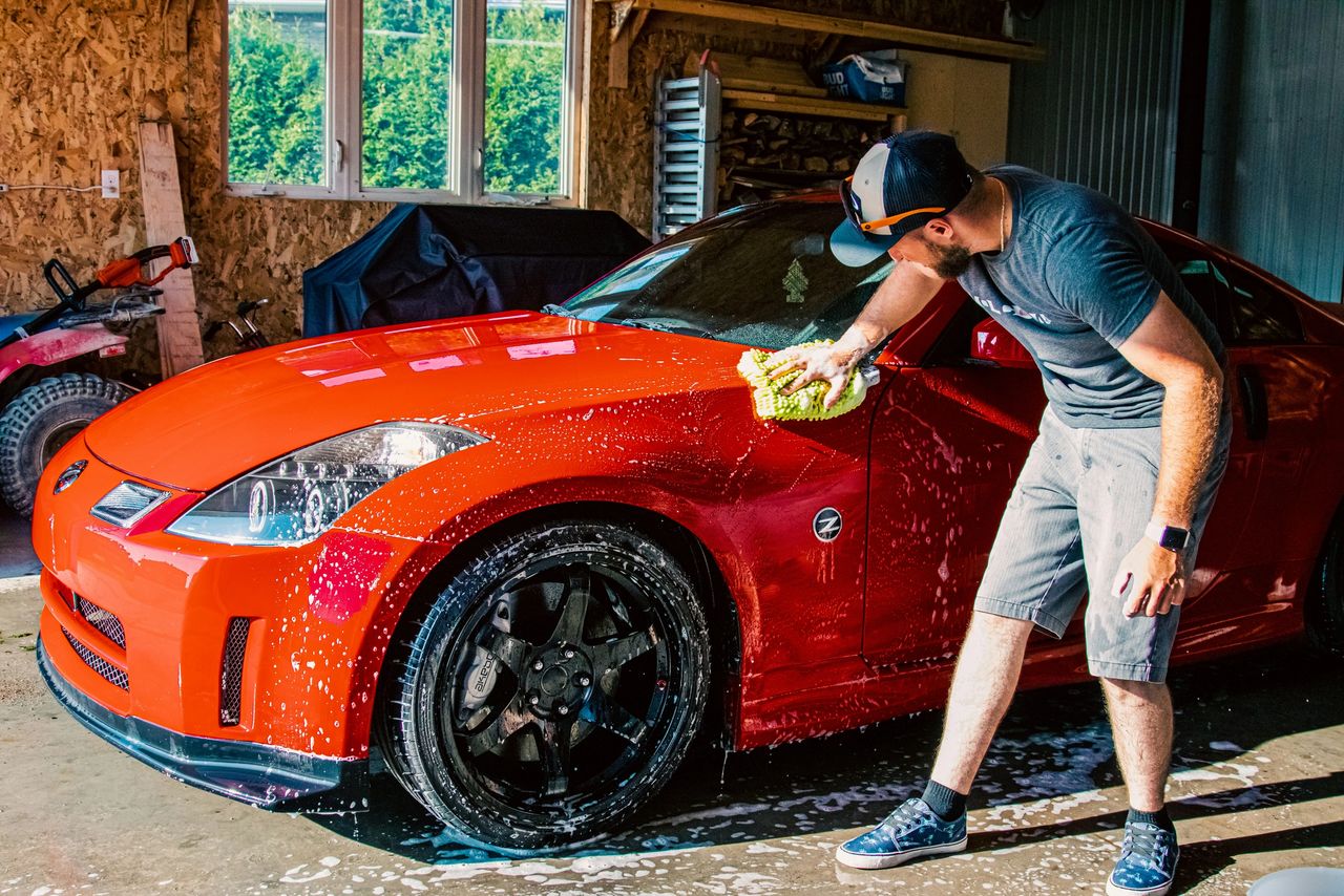 A man washing his red car