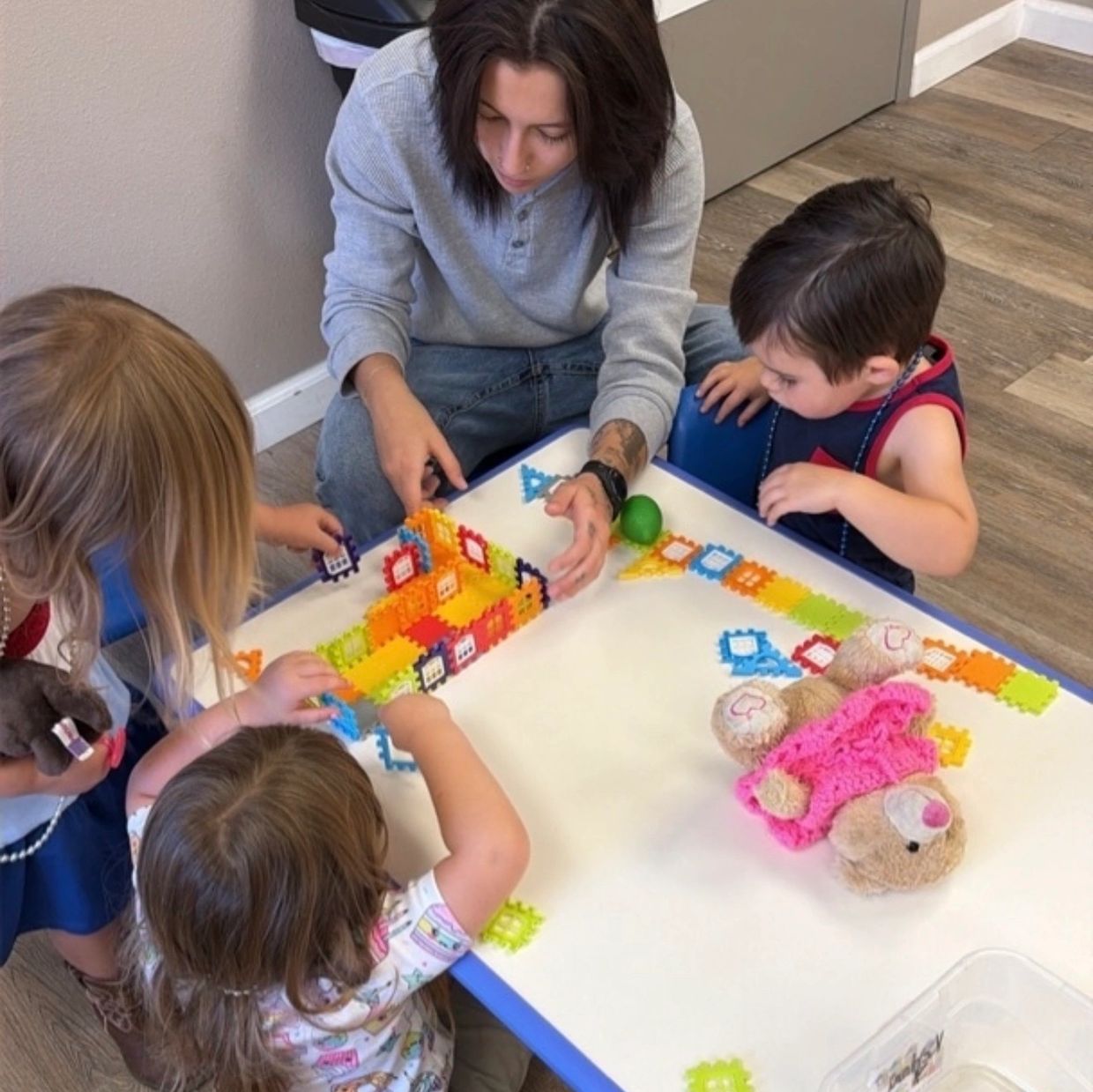 Adult and kids playing with colorful building blocks at a table.