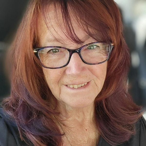 Smiling woman with glasses and red hair.