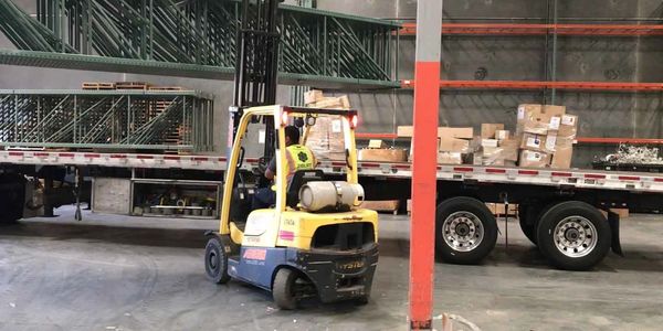 Back view picture of a worker loading a van using an electric forklift