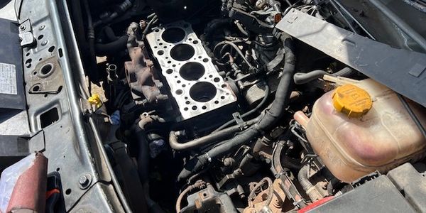 Car engine with cylinder head removed during repair.
