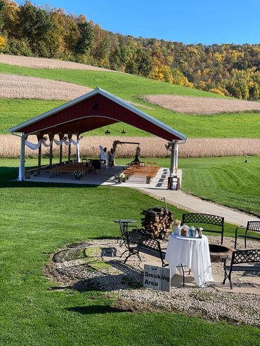 Outdoor pavilion and seating area in a scenic countryside setting with autumn foliage.