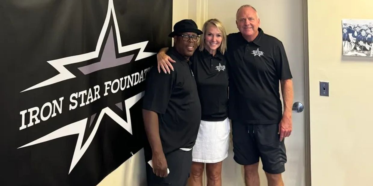 Three people standing by Iron Star Foundation banner.