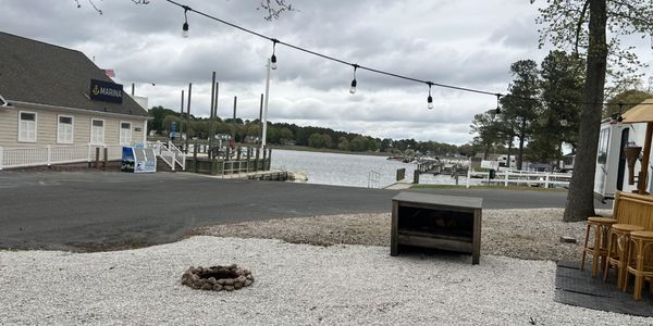 Quiet marina with boats docked and string lights overhead on a cloudy day.