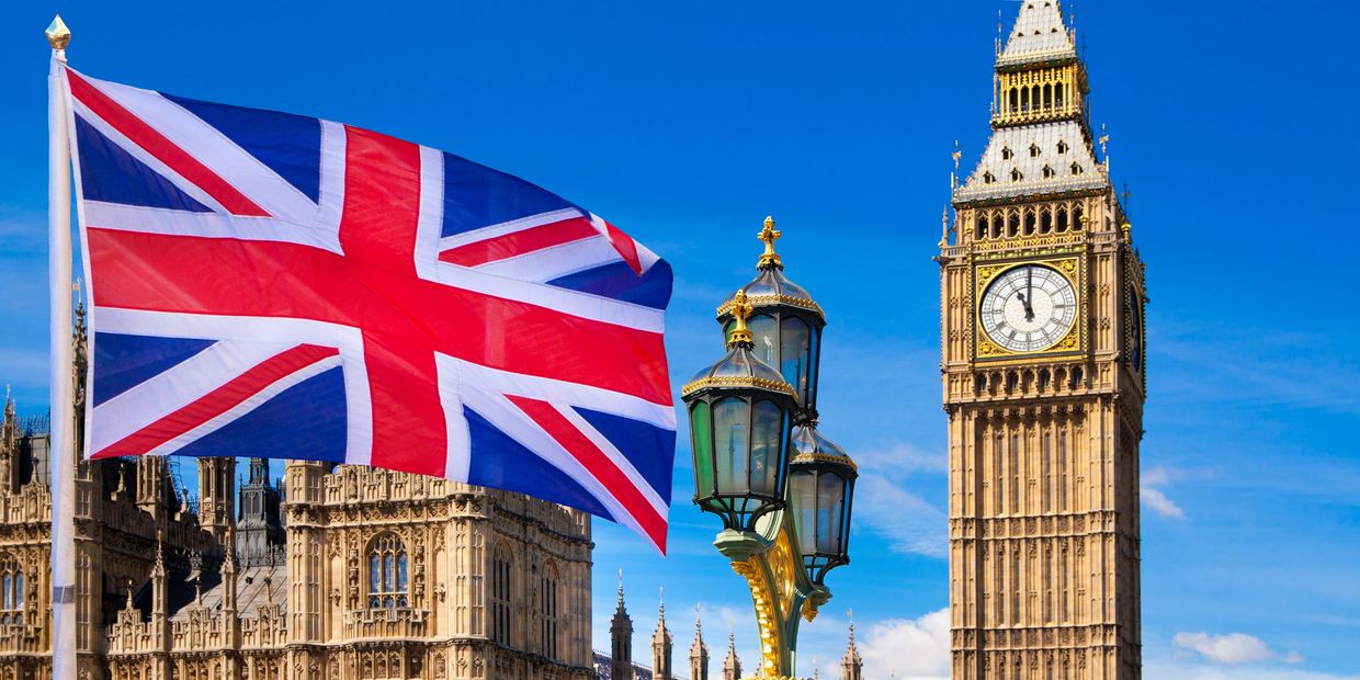 Union Jack flag flying near Big Ben in London on a clear day.