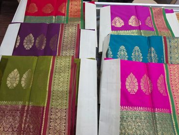 Colorful silk sarees with intricate gold and silver zari work.