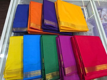 Colorful folded fabrics with golden borders arranged on a glass surface.