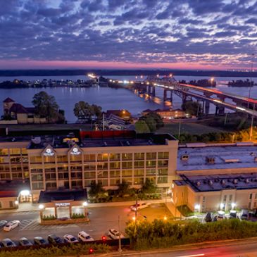 Cityscape at dusk with a river and bridge.