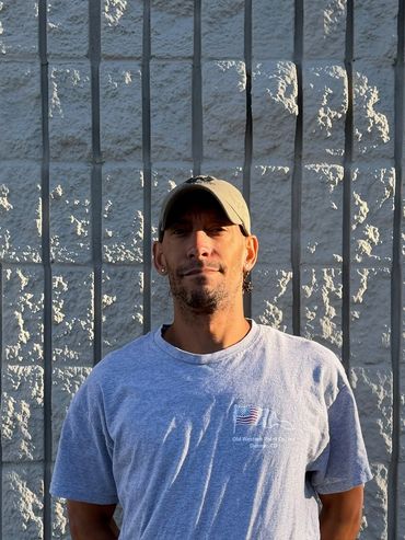 Man standing in front of a brick wall with vertical metal bars.