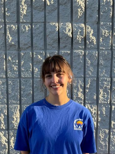 Young woman smiling in front of a textured wall.