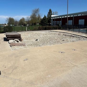Empty gravel pit with wooden planks and concrete surroundings.