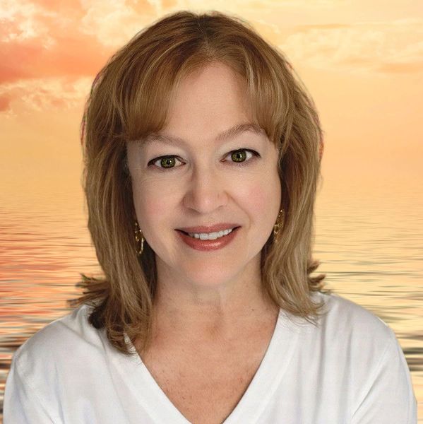 Smiling woman with light brown hair against a serene sunset ocean background.