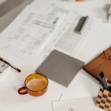 A cozy workspace with a cup of coffee, papers, and stationery on a white desk.