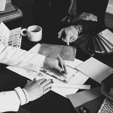 Two people discussing and working on architectural plans with material samples.