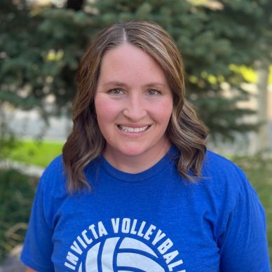 Smiling woman in a blue Invicta Volleyball t-shirt outdoors.