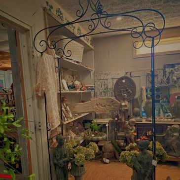 Eclectic vintage shop corner with statues, plants, and decorative items.