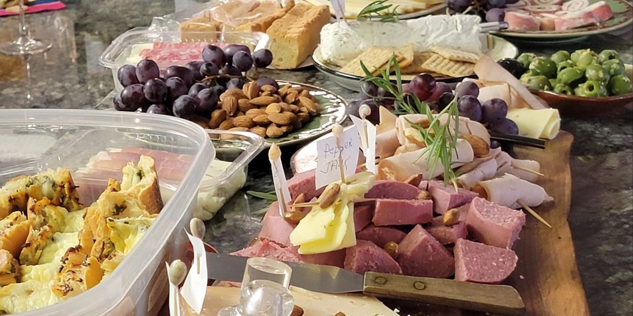 Showing a Charcuterie board set up with a wide variety of meats and cheeses plus other items.