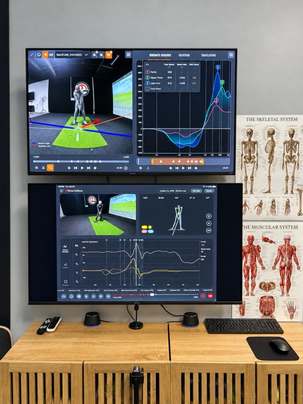Golf swing analysis setup with dual monitors and anatomical charts.