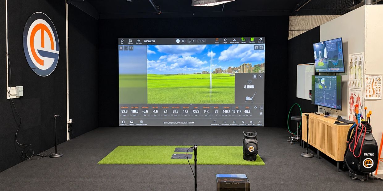 Indoor golf simulation room with digital screens.