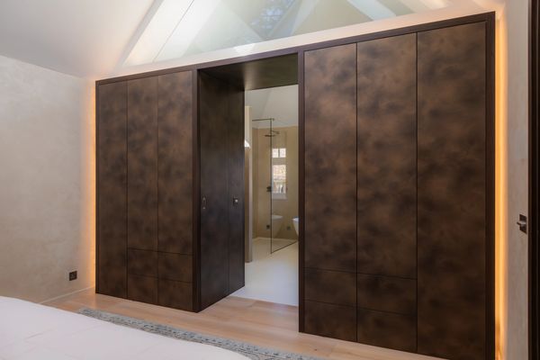 Modern bedroom with unique brown textured wardrobes and glass door to bathroom.