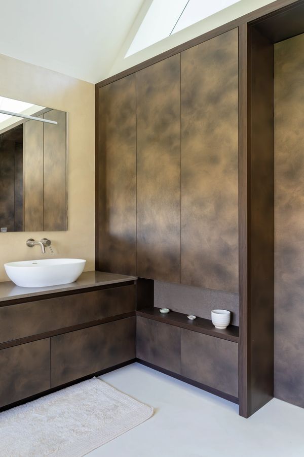 Modern bathroom with bronze-toned cabinets and a white vessel sink.
