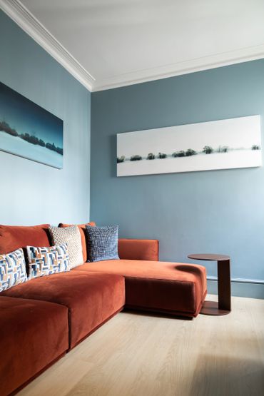 Modern living room with a rust-colored sofa and blue walls.
