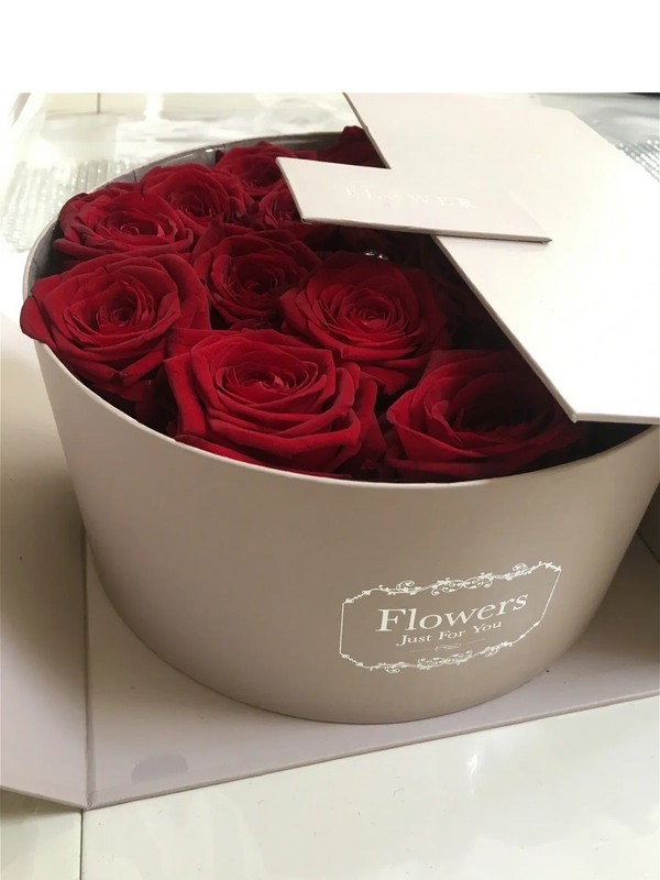 Round box filled with fresh red roses and a partially opened lid.