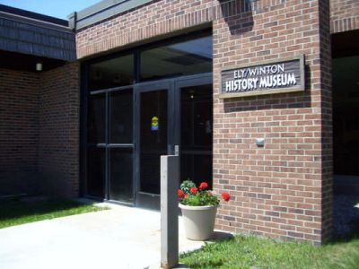 Entrance to the Ely Winton History Museum with a flower pot nearby.