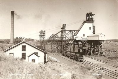 Historic mining site with industrial structures and rail tracks.