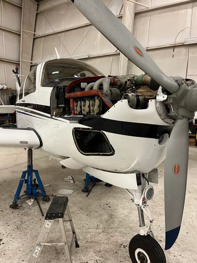 Light aircraft undergoing engine maintenance in a hangar.
