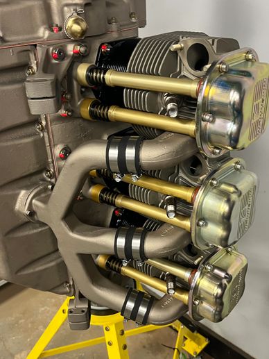 Close-up of a mechanical engine component mounted on a yellow stand.
