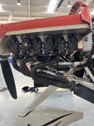 Close-up of an aircraft engine with exhaust pipes and propeller.