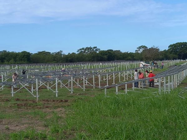 Construcción de una granja solar con estructuras metálicas y trabajadores.