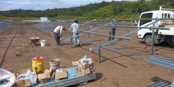Trabajadores montando estructura metálica en terreno abierto.