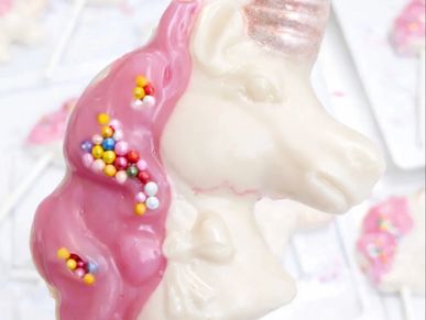 Close-up of a unicorn-shaped treat with pink icing and colorful sprinkles.