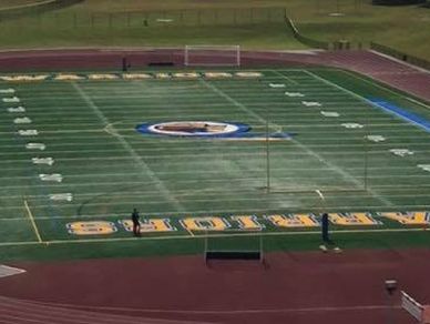 Empty football field with scoreboard and track surrounding it.