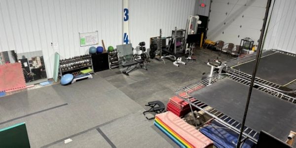 Interior view of a gym with exercise equipment and mats.