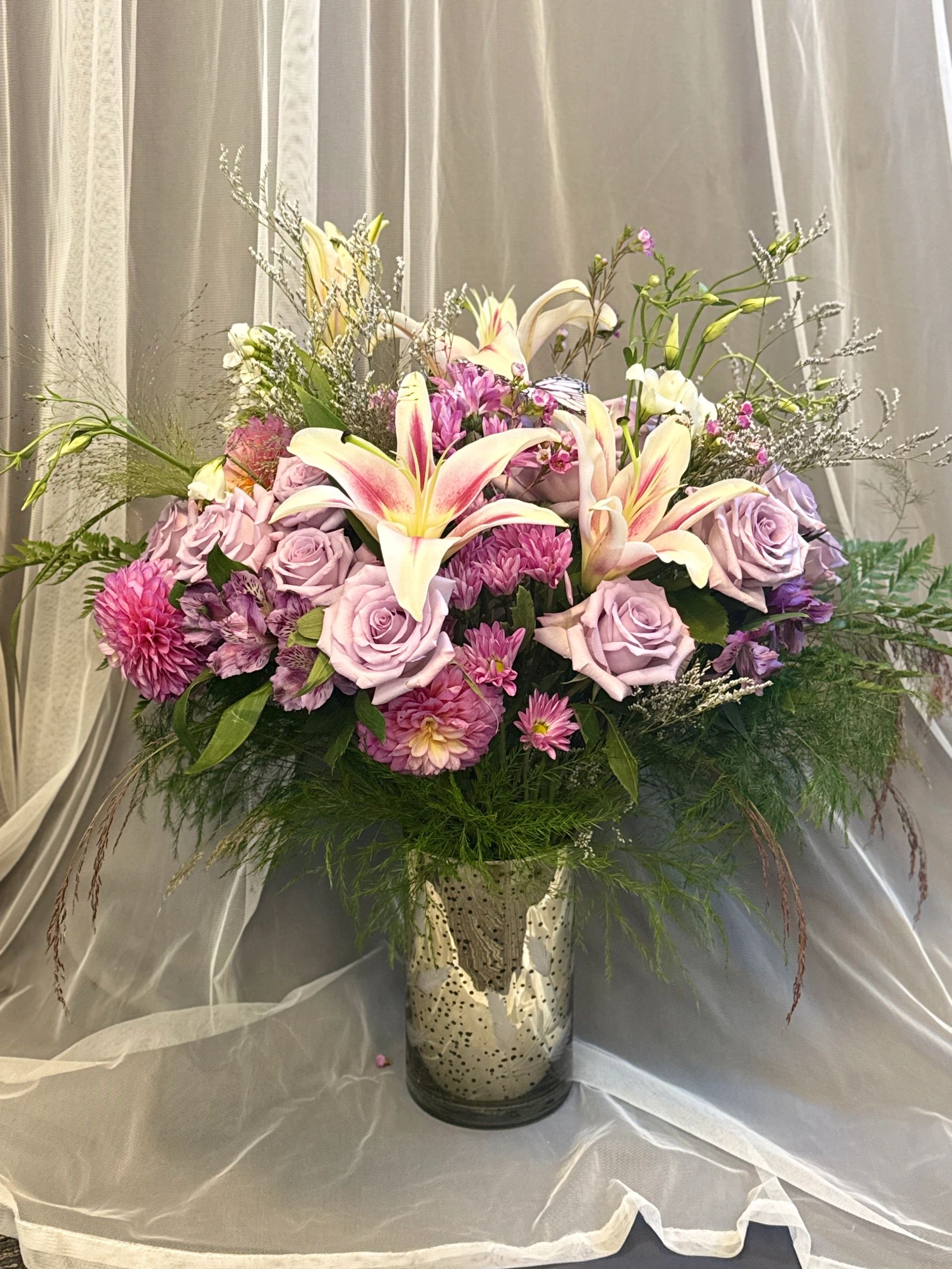 Elegant bouquet of lilies, roses, and chrysanthemums in a decorative vase.