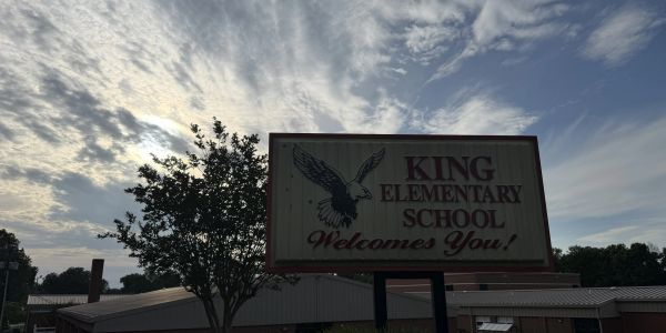 King Elementary School sign with sky and tree in background.