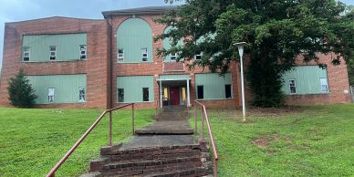 Old abandoned brick building with boarded windows.