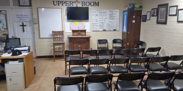 Small church room with chairs, cross, and religious decor.
