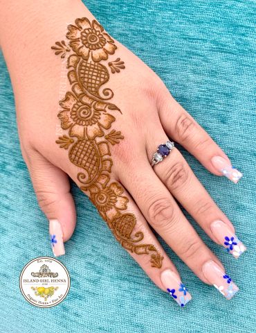 Intricate henna design on hand with floral nail art.
