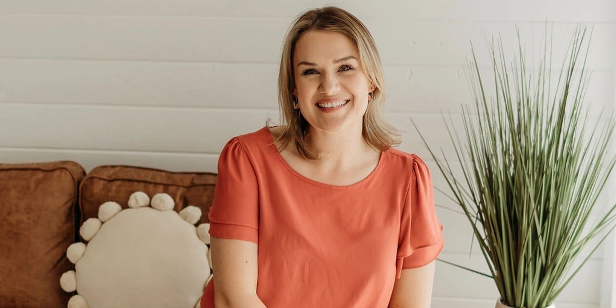 Woman sitting on a couch smiling.