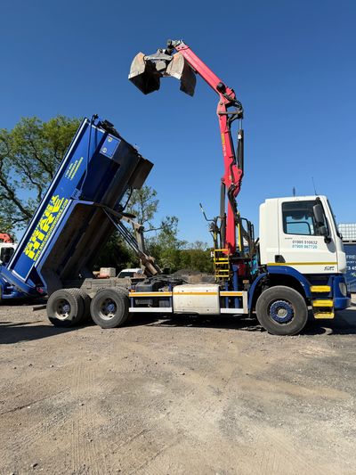 A blue and white truck with a red crane arm and an elevated blue container bed.