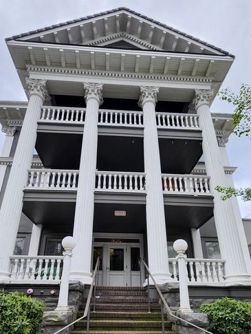 Front view of a large white neoclassical building with tall columns.