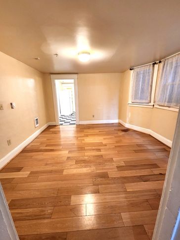 Empty room with wooden floor and beige walls.