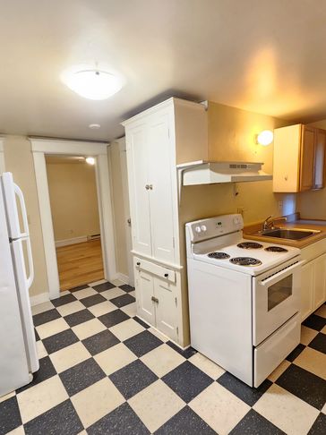 Compact kitchen with white cabinets and checkered flooring.